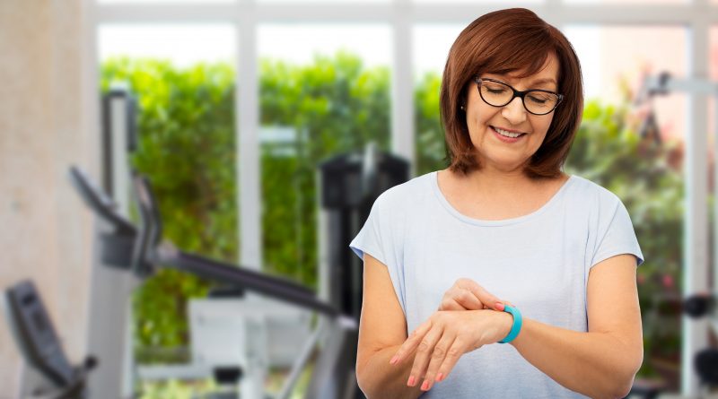 Adulta mayor sonriente con rastreador de fitness en el gimnasio