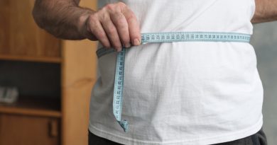 Hombre midiendo su vientre con cinta metrica de pie en la sala de estar