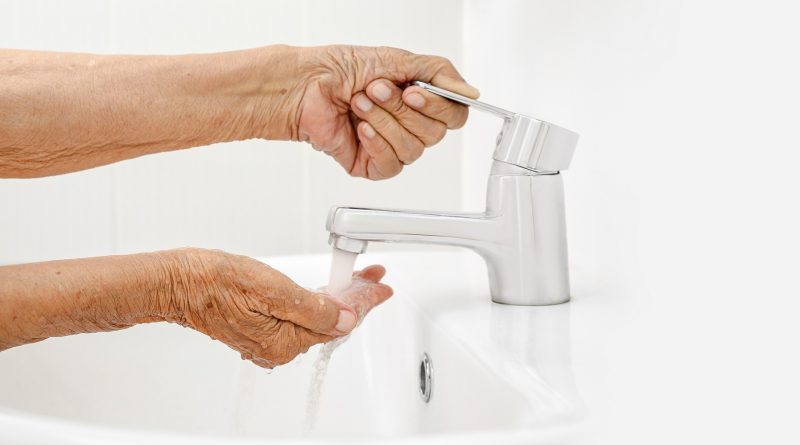 Adulta mayor se lava las mano en cuarto de baño