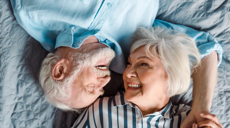 pareja de adultos mayores recostados en la cama felices y sonrientes